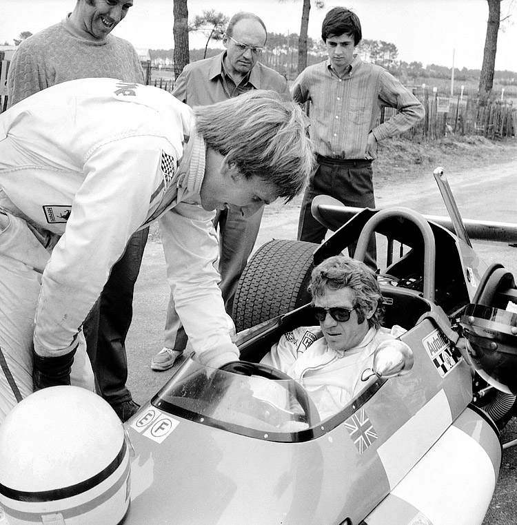 Steve McQueen au volant d'une Brabham F2, au Mans Le 18 Juillet 1970, à l'écoute du pilote de Formule 1 Derek Bell, qui lui donne quelques conseils. Steve Mc Queen est au Mans  pour agir en tant que pilote dans la Preston Sturges du film «Le Mans». © Crédit photo / AFP / Getty Images