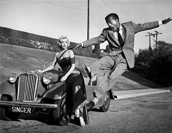 Marylin Monroe à côté d'une belle voiture, est en admiration devant Sammy Davis Jr en pleine danse