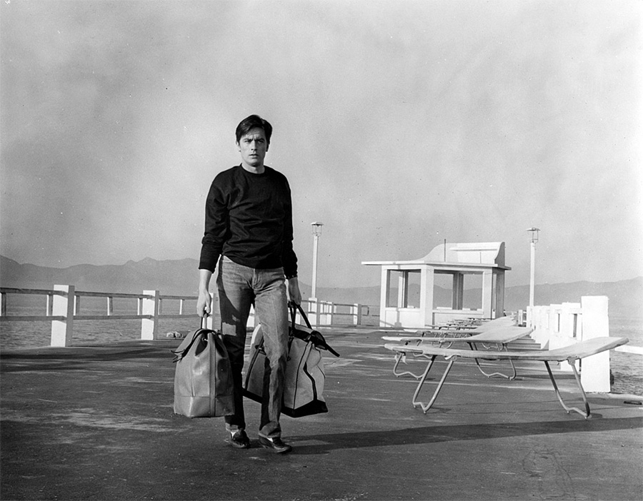 Alain Delon transportant des sacs de billets durant le tournage du film "Mélodie en sous-sol" d'Henri Verneuil - 1963 © Photo sous Copyright